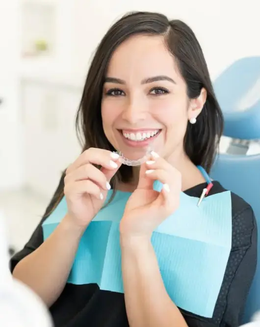 Invisalign Sherman Oaks - Patient holding Invisalign aligners next to a treatment progress - Sherman Oaks Smile Studio